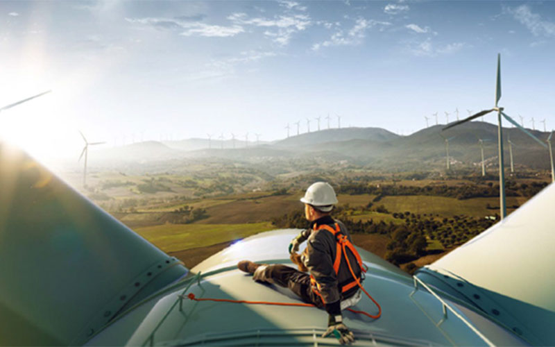 Tecnician sitting on top of a windmill