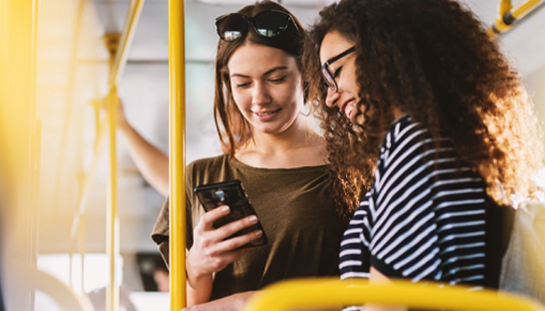 Two smiling students travelling by public transport