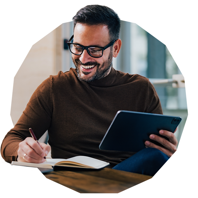 Smiling man taking notes while on a call
