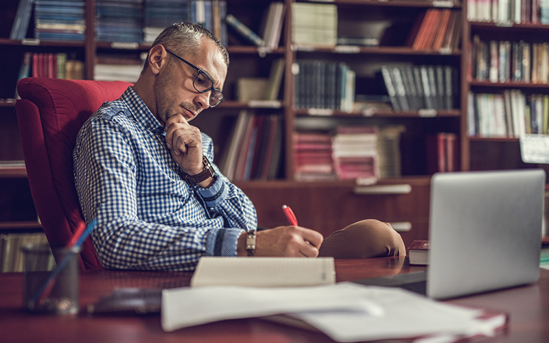 Business professional writing at his desk in his home office