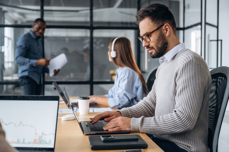 Man-sitting at a desk while working on a laptop