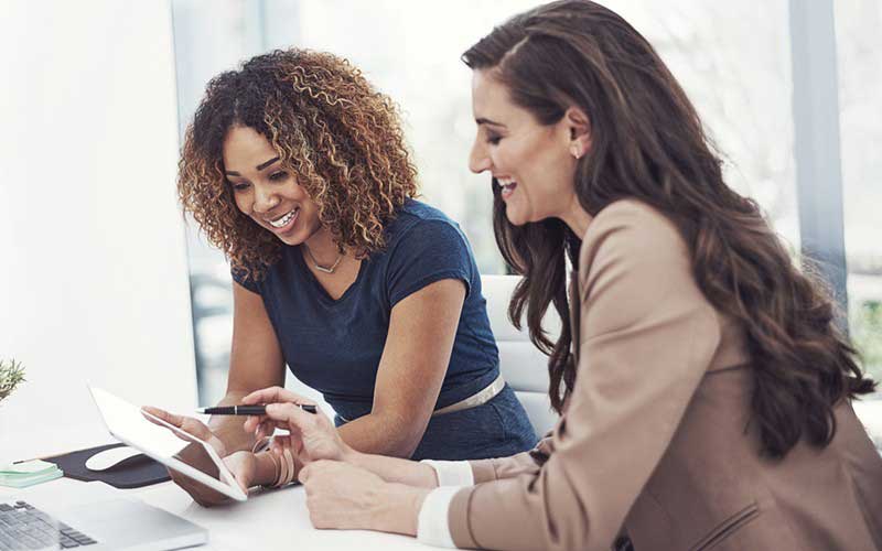 Two woman smiling looking at tablet