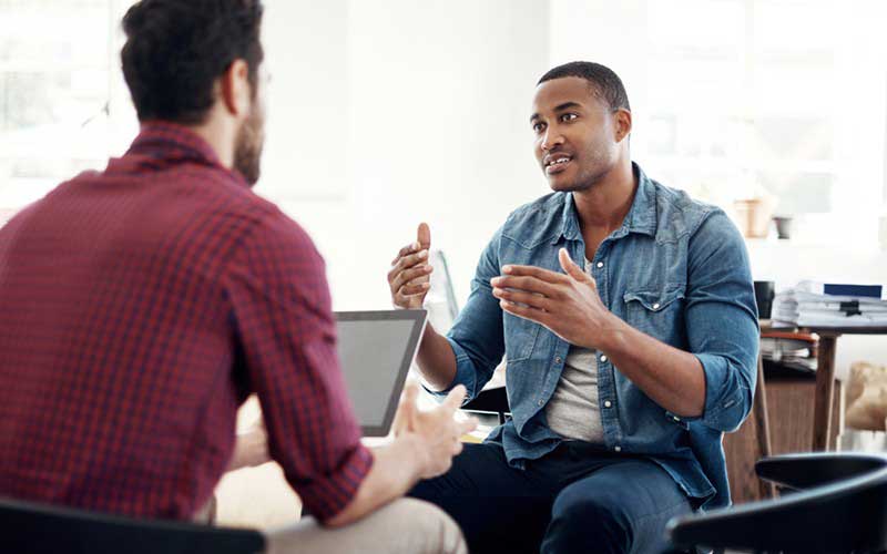 Young men having a discussion over a laptop