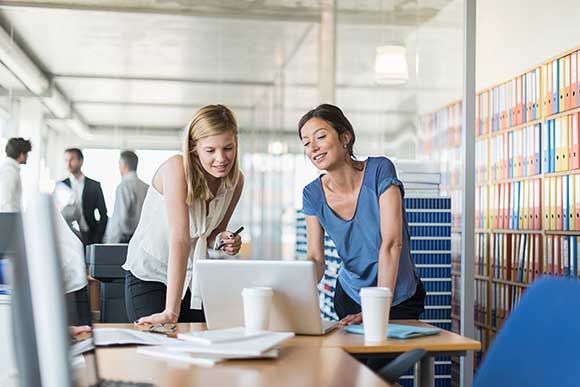 Businesswomen have discussion at desktop computer in office