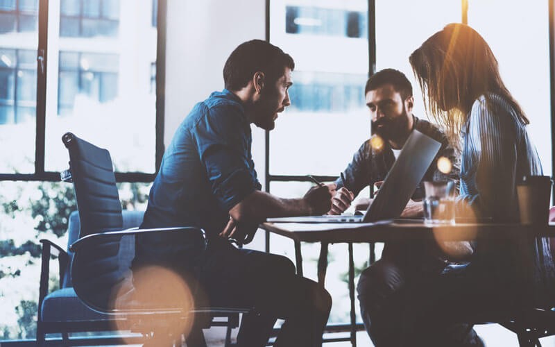 Group of colleagues sat around a desk working together