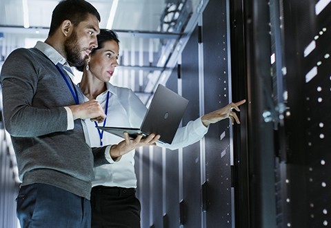 Two IT technicians working in a server room