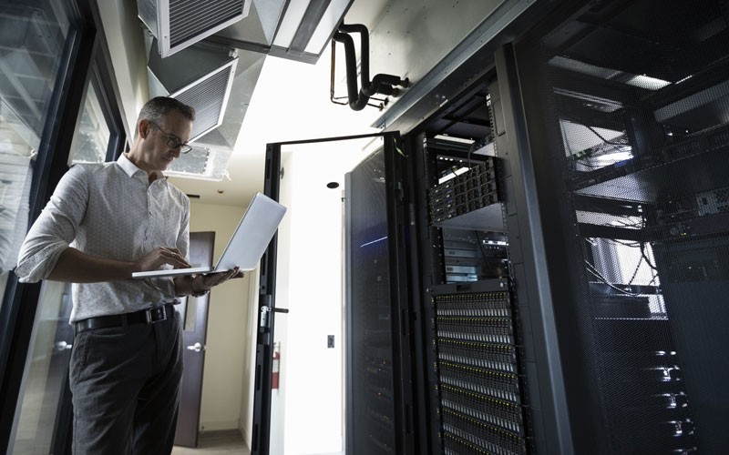 IT technician working on laptop in a data centre