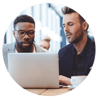 Two males working together over laptop device