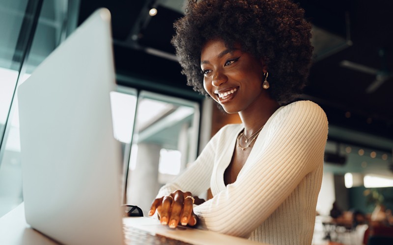 woman-working-on-laptop-in-office Woman smiling while looking at a screen