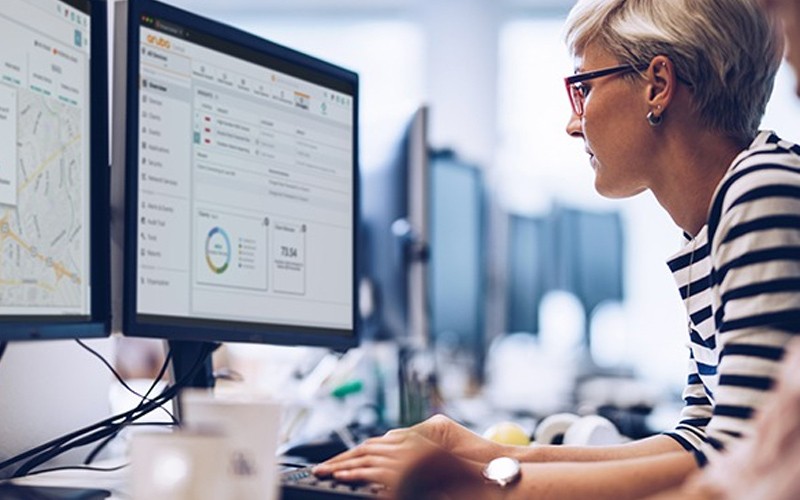 Aruba Clearpass Woman sat at desk with computer.