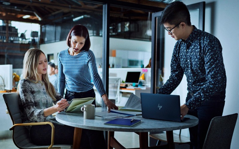 Team at work Three people working at a desk on a project using HP laptop
