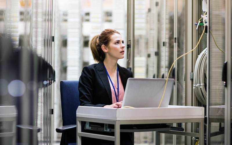 Stop advanced threats and protect critical assets Woman working at a small desk attached to a data center