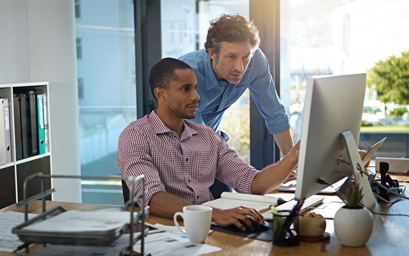 Get the performance of a laptop and the versatility of a tablet Team has a candid meeting in hallway and uses a Microsoft Surface Pro 2-in-1 computer