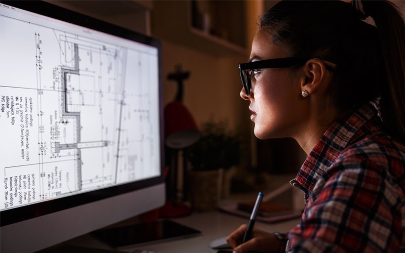 Architect woman working at night on computer using large file size