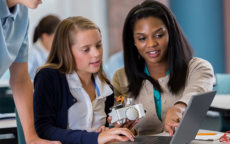 Laptops tough enough for the military Teacher holding a Lenovo device while teaching a class