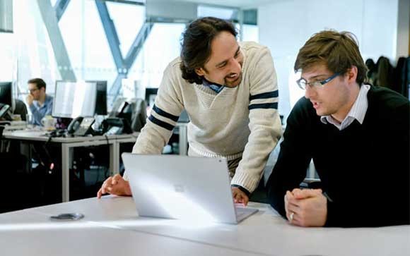 Two colleagues working together at a Microsoft laptop Microsoft offer customizable licensing options for both software and hardware