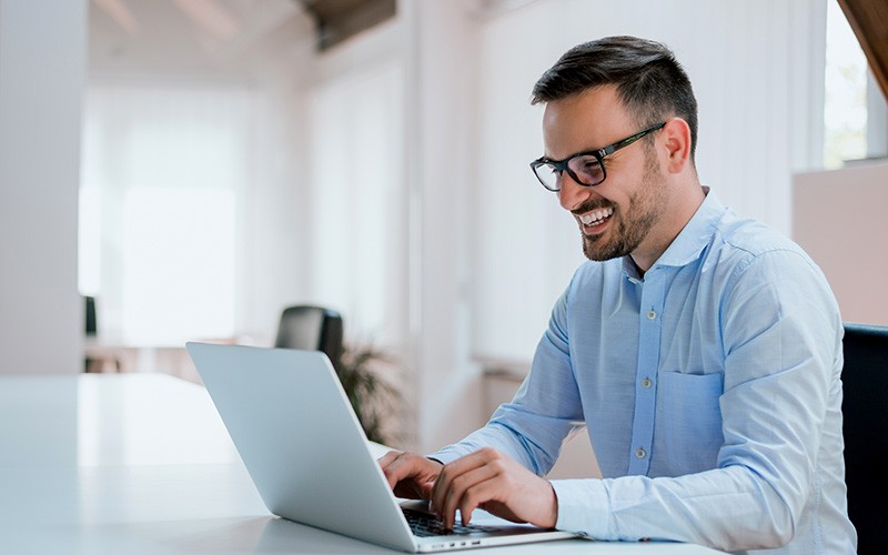 Man smiling while working on a laptop