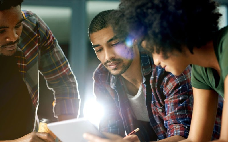 Three individuals looking over tablet
