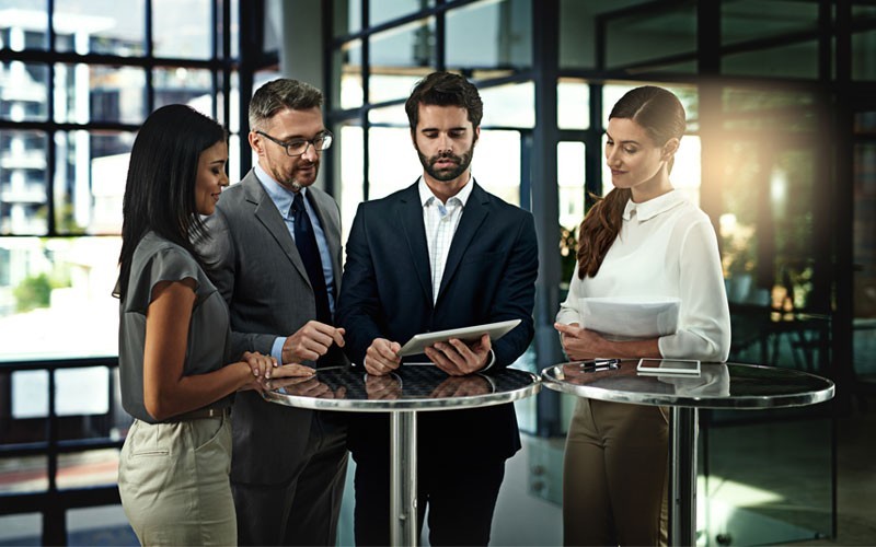 Group of employees looking over tablet at high table