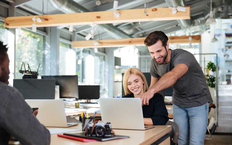 Two employees helping each other with laptop device
