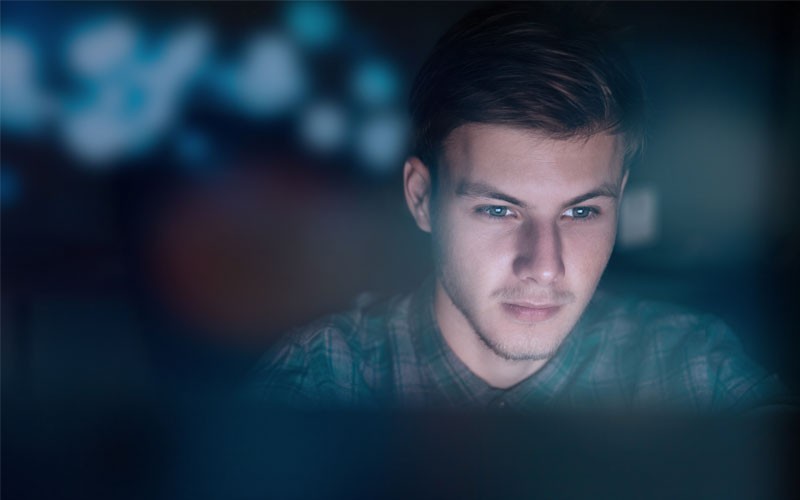 Male user looking at monitor at night